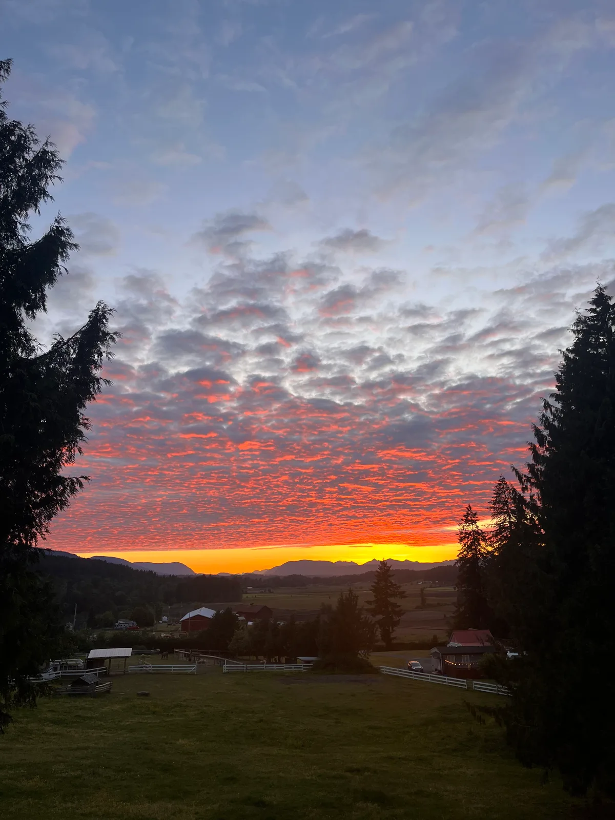 Red and pink sunset clouds over a valley and distant hills